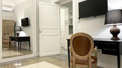 a chair in a room with a desk and a mirror at Dimora Borghese “Whitaker” in Palermo