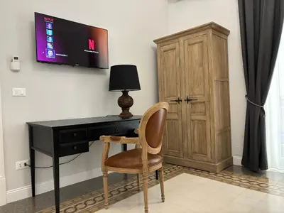a desk with a chair and a television on a wall at Dimora Borghese “Whitaker” in Palermo