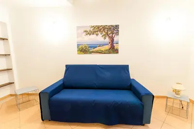 a blue couch in a room with a painting on the wall at Trinity Apartments in Castellammare del Golfo