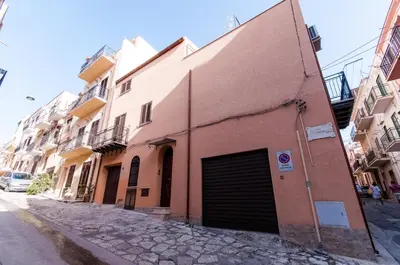 a building with a garage on the side of a street at Trinity Apartments in Castellammare del Golfo