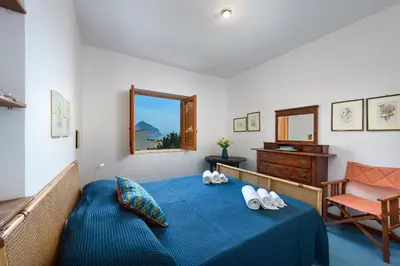 a bedroom with a blue bed and a chair at Casa ChiaraMarina in Macari