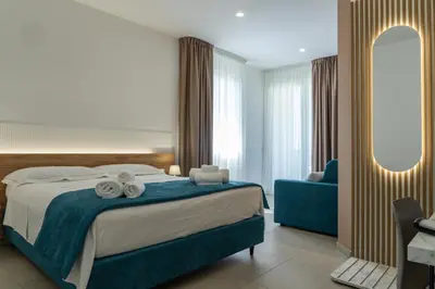 a bedroom with a large bed and a blue chair at B&B Alba in Terrasini
