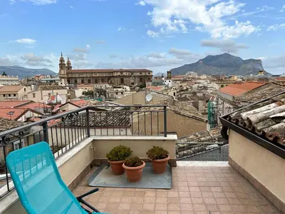a blue chair on a balcony with a view of a city at Casa Design con terrazzo in centro storico a Palermo in Palermo