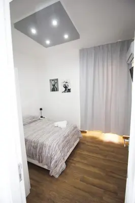 a white bedroom with a bed and a wooden floor at La chiave dei sogni in Palermo