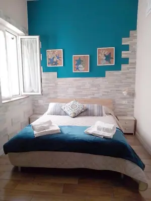 a bedroom with a large bed with a blue wall at Casuzza Bedda e Duci in Mondello