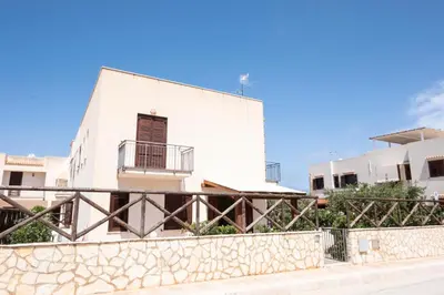 a white building with a fence in front of it at Casa Orchidea Bianca in San Vito lo Capo
