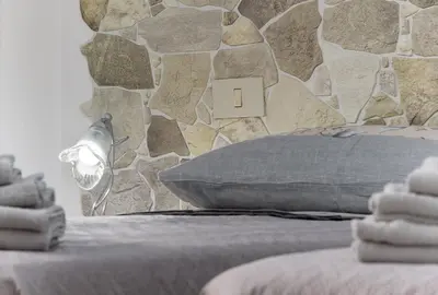 a bedroom with a stone wall and a bed with a pillow at Bedda Luna Villa in San Vito lo Capo