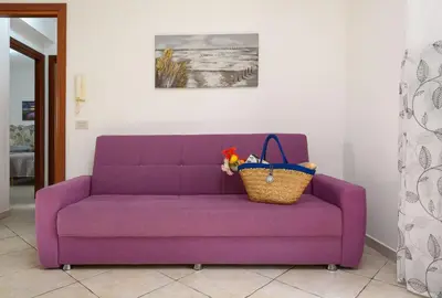 a purple couch with a basket on top of it at Bedda Luna Villa in San Vito lo Capo