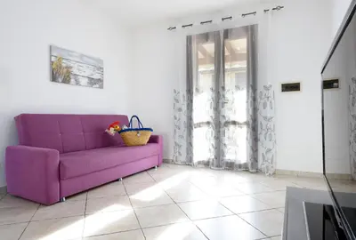 a purple couch in a white room with a window at Bedda Luna Villa in San Vito lo Capo