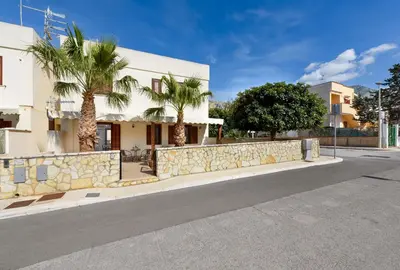 a building with palm trees on the side of a street at Bedda Luna Villa in San Vito lo Capo