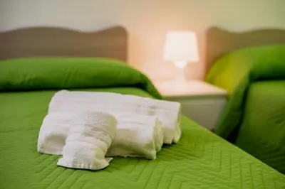 a pile of towels sitting on a green bed at VILLA HEMINGWAY - LA Casa di Alessia e La Casa di Leonardo in Ficarazzi