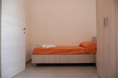 a small bedroom with a bed with an orange blanket at Villa Marica in Partinico