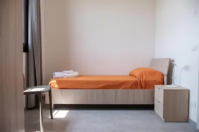 a bedroom with a bed with an orange blanket and a chair at Villa Marica in Partinico