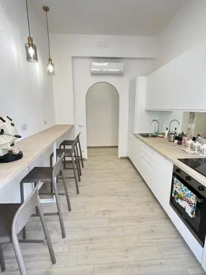 a kitchen with white cabinets and a counter with chairs at Bella Vita Palermo in Palermo