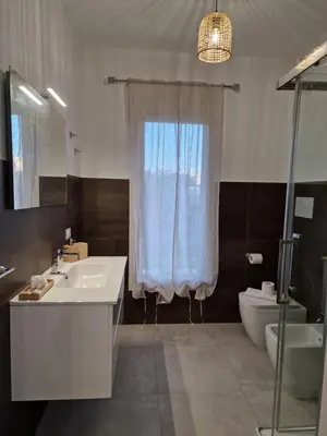 a bathroom with a sink and a toilet and a window at Villa Fragi in Cinisi