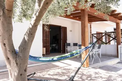 a hammock in a tree outside a house at Casa Orchidea Nera in San Vito lo Capo