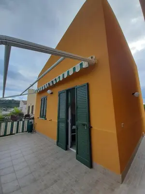 a yellow and green building with green shutters at Casa Vacanze Isabella in Campofelice di Roccella