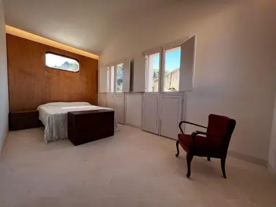 a bedroom with a bed and a chair and windows at Palazzo Triolo - Dimora di Charme in Corleone