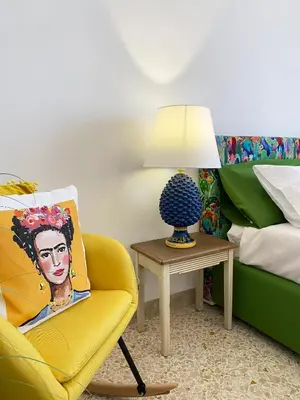 a bedroom with a yellow chair and a table with a lamp at Casa Graziusa in Palermo