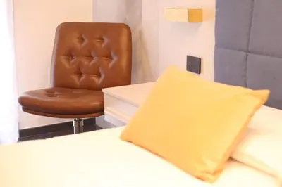 a brown leather chair next to a bed with a yellow pillow at Guest House Colonna in Palermo