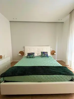 a bedroom with a large bed with a green blanket at wood & white home in Palermo