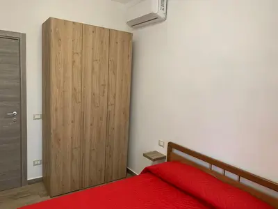 a bedroom with a red bed and a wooden closet at La Villa degli Ulivi - Apartments in Castellammare del Golfo