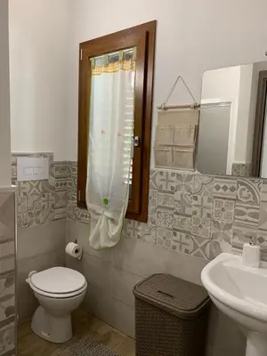 a bathroom with a toilet and a sink and a mirror at La Villa degli Ulivi - Apartments in Castellammare del Golfo