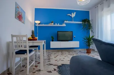 a living room with a blue wall with a television at Sea Air - Aria di Mare in Casteldaccia