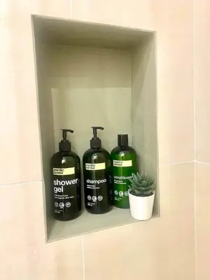 a shelf with four bottles of shower gel and a plant at Sikelia Apartment Centro in Palermo