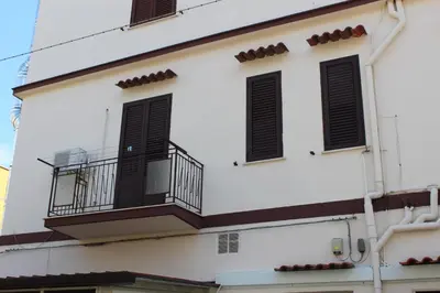 a white building with a balcony and black shutters at Mondello Blue Sea in Mondello