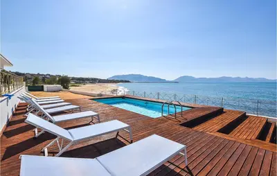 a deck with chairs and a swimming pool next to the water at Nice Home In Balestrate in Balestrate