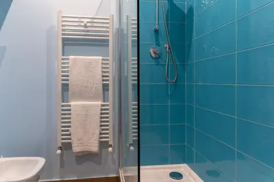 a bathroom with a shower with blue tiles at Libertà #102 - Guest House Palermo in Palermo