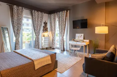 a bedroom with a bed and a desk and a television at Libertà #102 - Guest House Palermo in Palermo