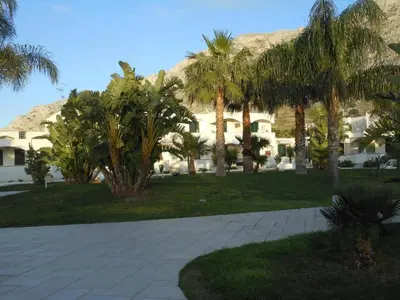 a courtyard with palm trees and a building at Le Palme House Isola delle Femmine in Isola delle Femmine