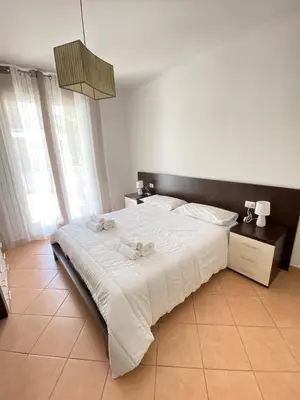 a bedroom with a large bed with white sheets at Le Palme House Isola delle Femmine in Isola delle Femmine
