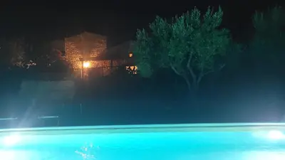 a swimming pool at night with a house in the background at Villa Jesabel in Scopello
