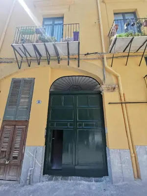 a building with a green door and a balcony at Vicolo Paternò Apartments in Palermo