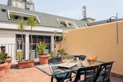 a glass table and chairs on a patio with plants at Vicolo Paternò Apartments in Palermo
