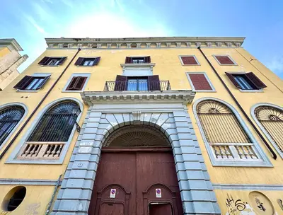 a tall yellow building with a door and an arch at Casa Guilla_alla Cattedrale in Palermo