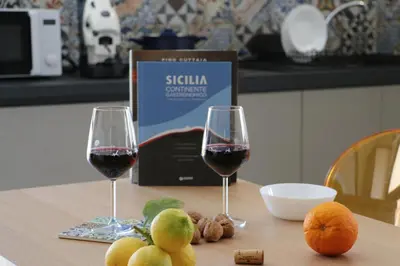 two glasses of wine and some fruit on a table at Elimi Home Appartamenti in Nuova Gibellina