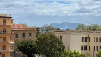 a view of two buildings with mountains in the background at Large flat near Botanical Garden & Central Station in Palermo