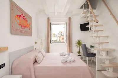 a white bedroom with a pink bed and a spiral staircase at Iverlid Home. in Palermo